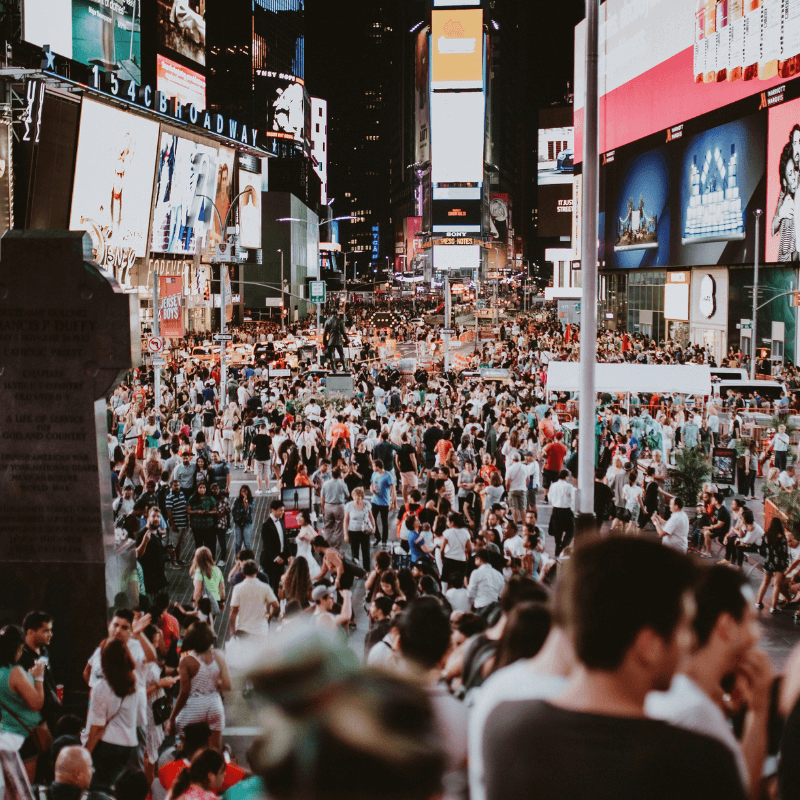 A crowd of people on the street surrounded by buildings and huge billboards